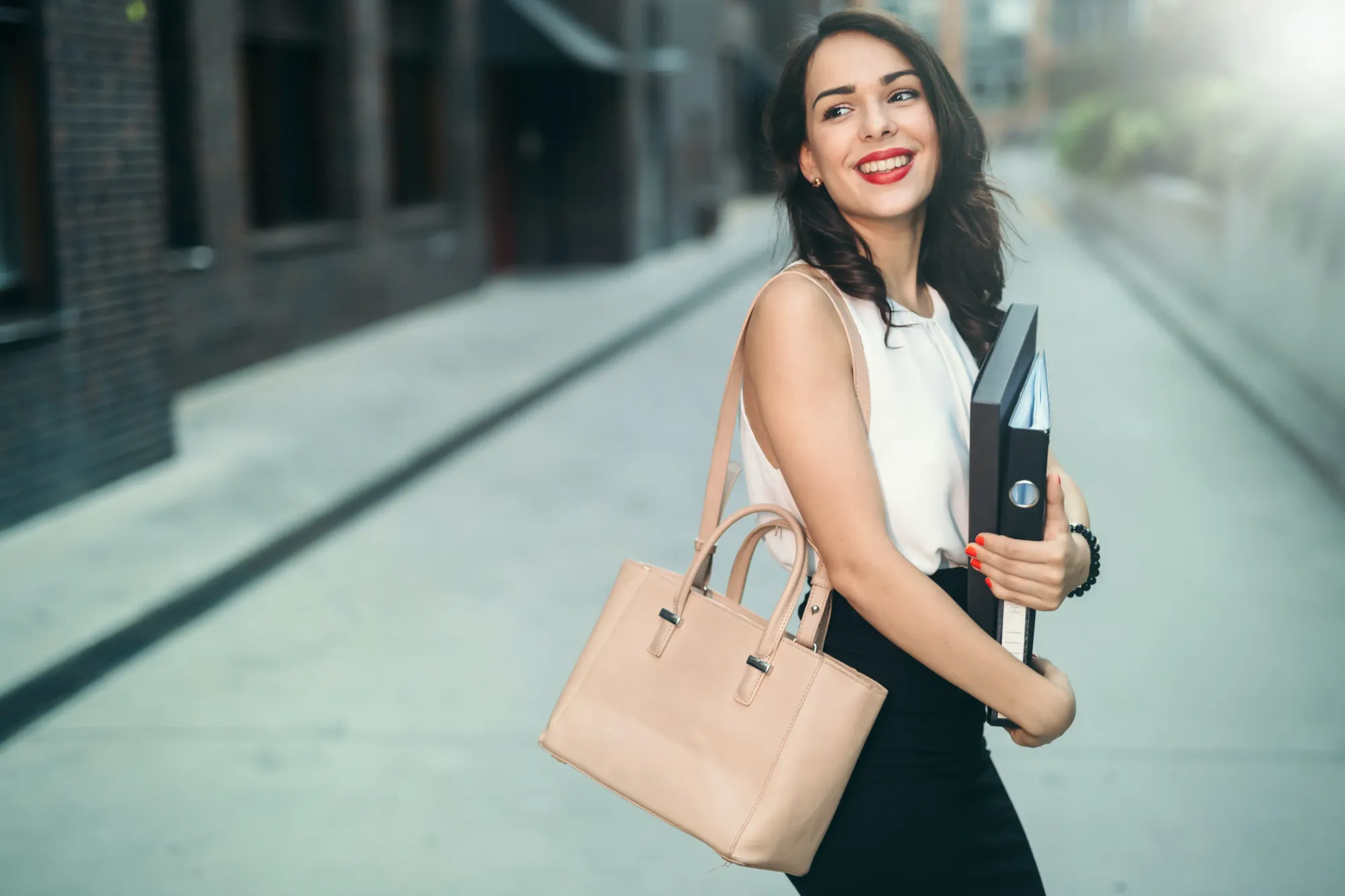 business woman smiling while holding purse and binders