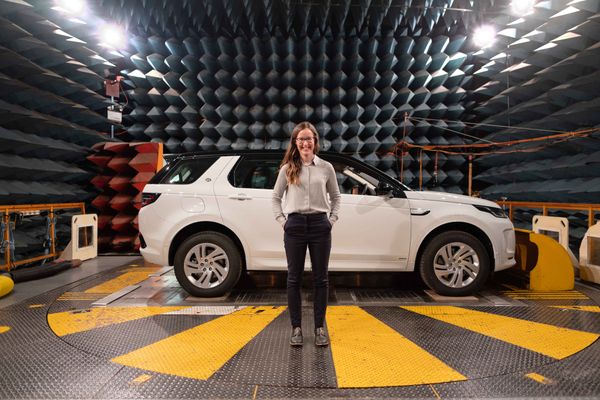 woman engineer standing in front of car in factory